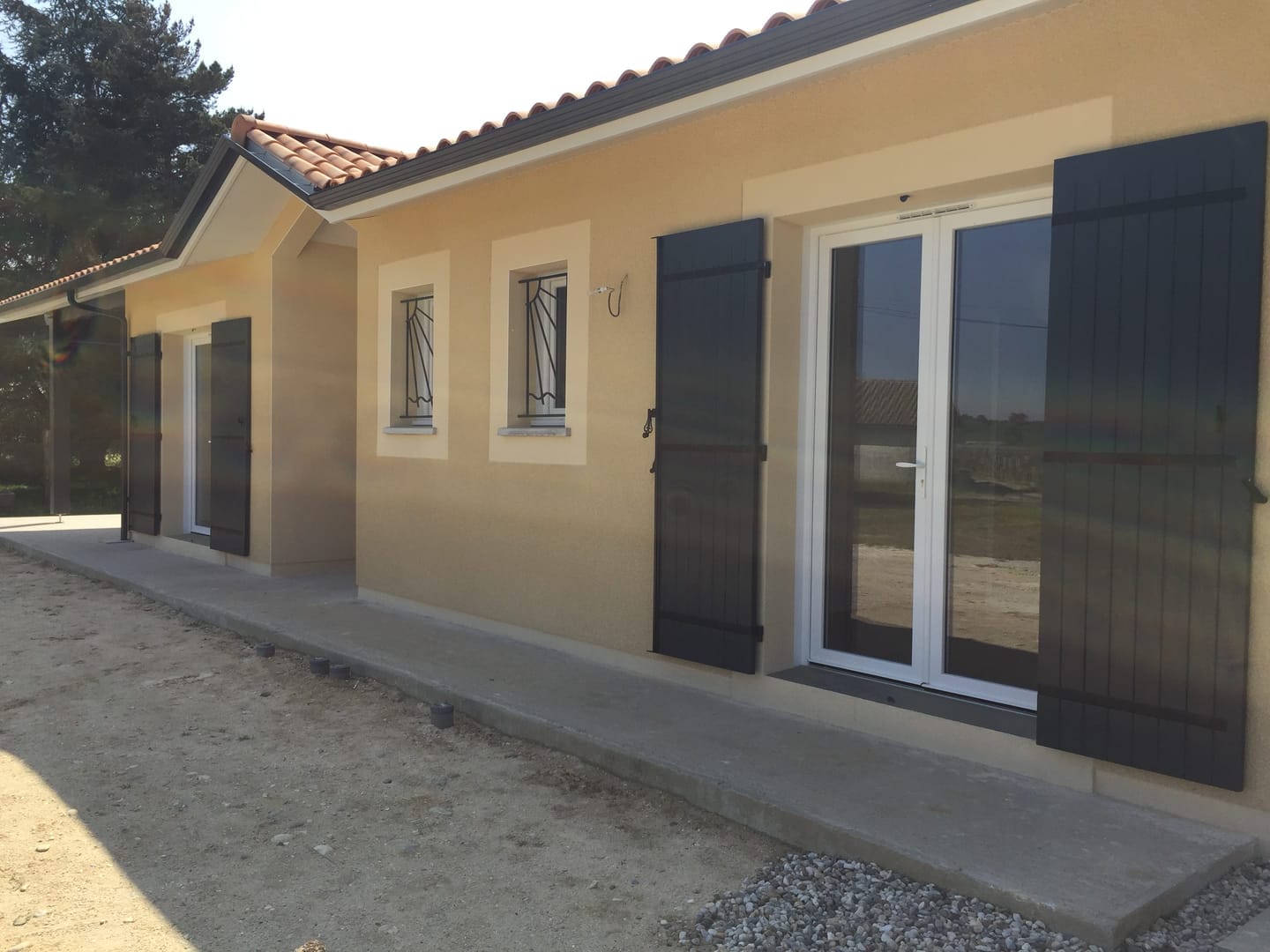 Maison moderne avec volets noirs et façade beige élégante